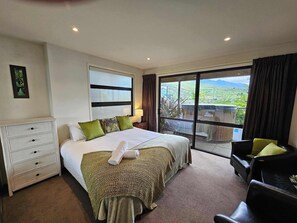 A hotel room with a large bed, a desk, a chair, and a view of the countryside.