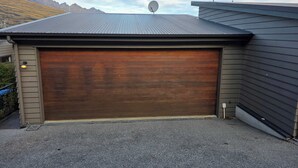 Un garage avec une porte marron, des antennes paraboliques sur le toit et une chaîne de montagnes en arrière-plan.