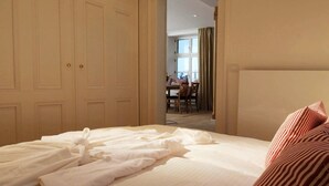Une chambre d’hôtel avec un lit bien fait, un coin repas à l’arrière-plan et une grande armoire.