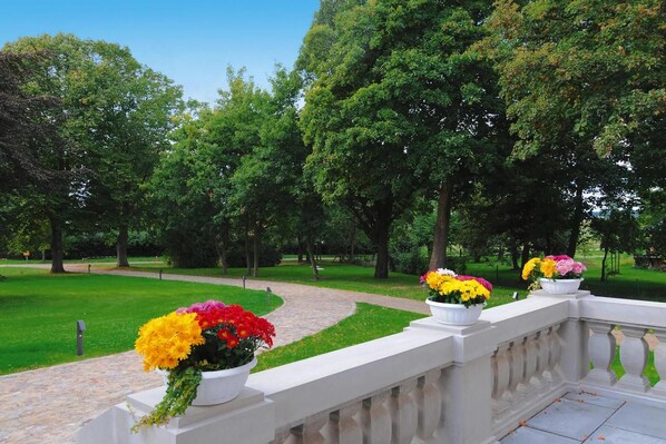 A garden with a paved walkway and white planters with flowers. - Gutshaus Zicker in Garz (Garz)