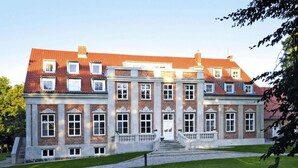 A large, historic building with a symmetrical facade, multiple windows, and a central entrance with steps. - Gutshaus Zicker in Garz (Garz)