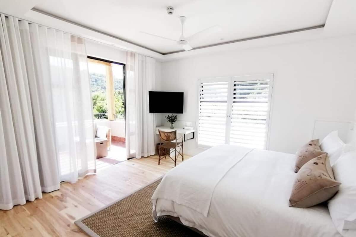 Un dormitorio con una cama grande, televisión y vistas al exterior.
