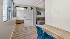 A compact room with a bed, a sofa, a dining table, and a sliding door. - Modern Condo Near Waikiki Beach & Free Parking (Honolulu)