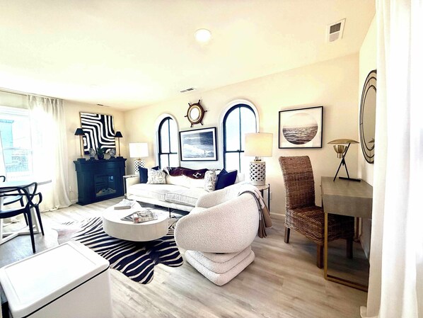 A modern living room with a sofa, armchairs, a coffee table, and a dining area.