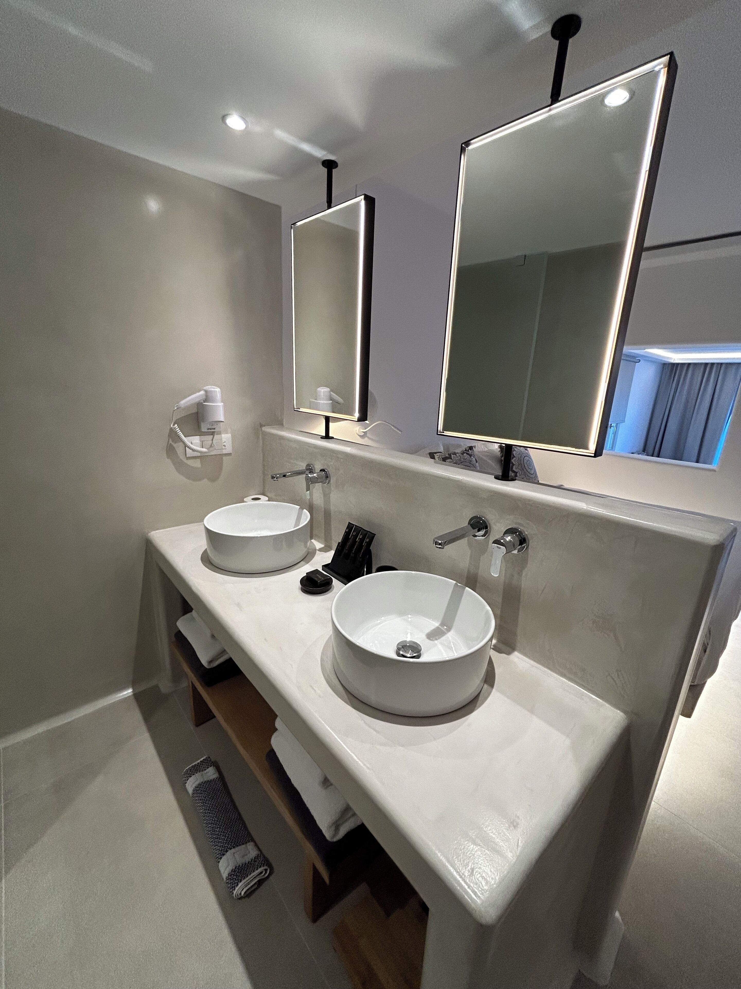 A modern bathroom with two white sinks, a mirror, and a towel rack.