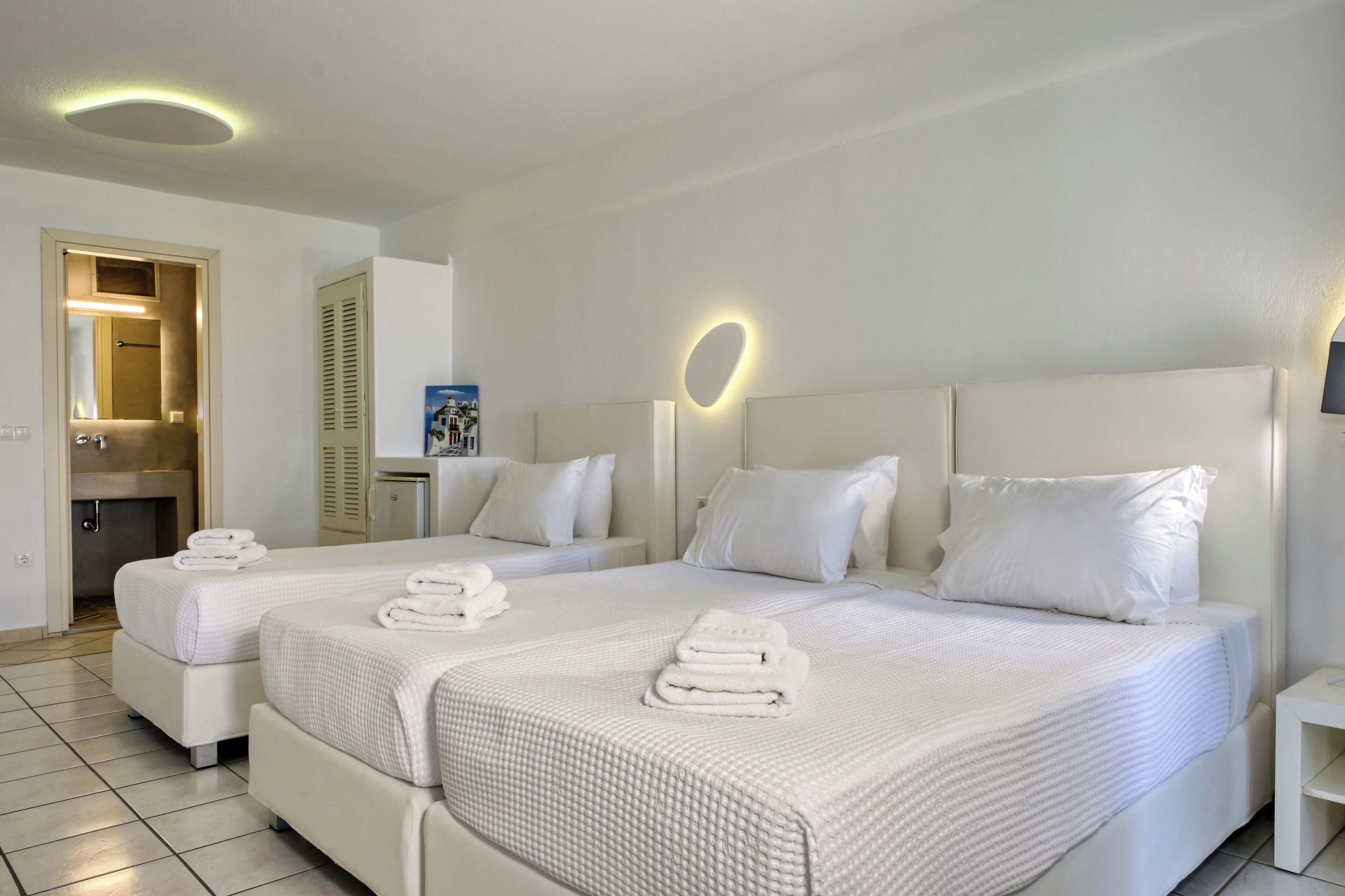 Hotellihuone, jossa on kaksi sänkyä, kylpyhuone ja suihkutila.