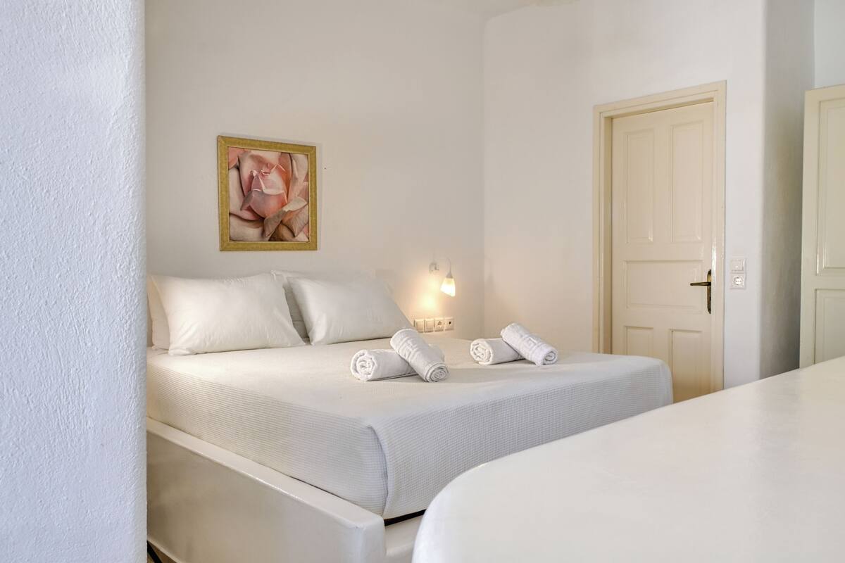 Quarto de hotel com uma cama, um quadro na parede, um abajur e uma porta.