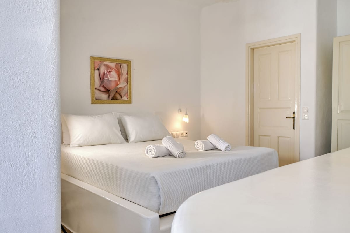 A hotel room with a bed, a painting on the wall, a bedside lamp, and a door.