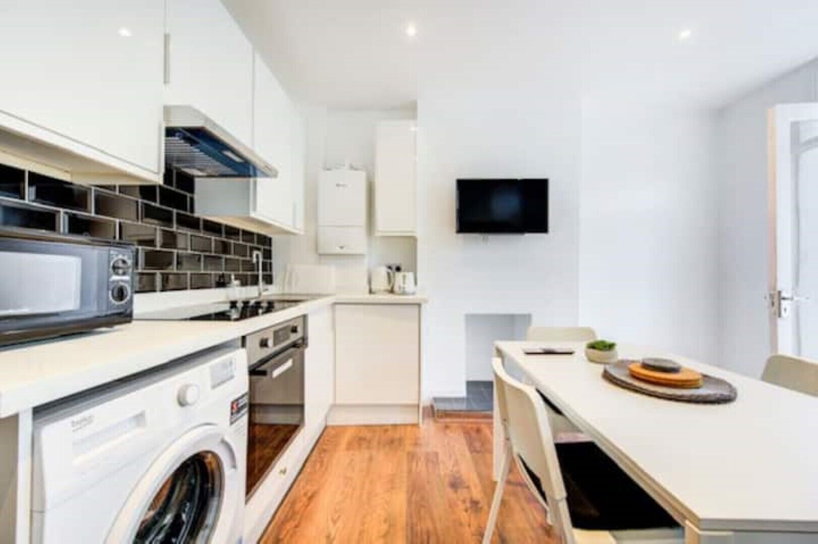 A compact kitchen with a microwave, stove, and washing machine.