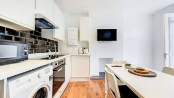 A compact kitchen with a microwave, stove, and washing machine.
