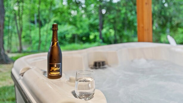 A hot tub with a bottle and a glass of water on its edge.