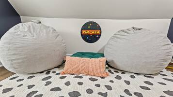 A room with a white headboard, a Pac-Man themed wall decal, and a patterned rug.