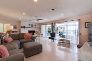 A spacious living room with a grey sectional sofa, a wooden coffee table, and a flat-screen TV.