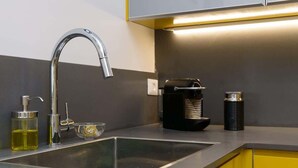 Una cocina moderna con un lavamanos de acero inoxidable, un grifo, un dispensador de jabón y una cafetera.