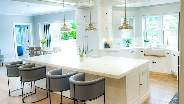 A spacious kitchen with a large island, bar stools, pendant lights, and a view of the outdoors. - Cluain Ard Holiday Home (Castletown)