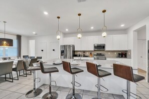 A modern kitchen with white cabinets, stainless steel appliances, and a central island with bar stools.