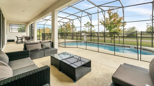Uma área externa coberta com piscina, assentos e vista para o exterior.