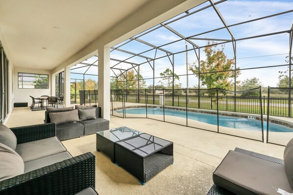 A covered outdoor area with a pool, seating, and a view of the outdoors.