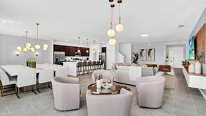 A modern living room with a dining area, kitchen, and a staircase leading to another level.