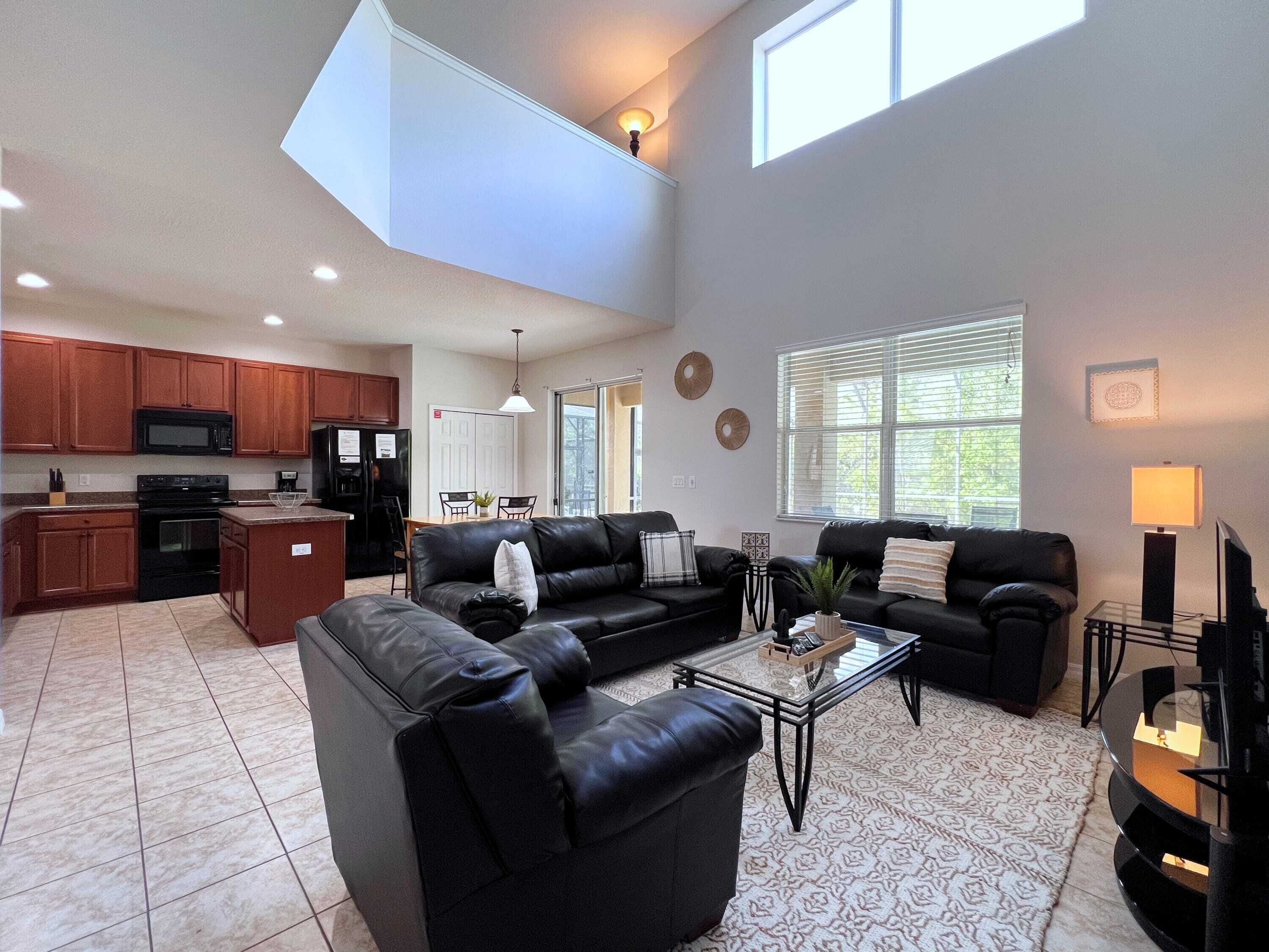 A spacious living area with a high ceiling, a kitchen with modern appliances, and a dining area.