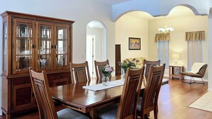 Una sala da pranzo con tavolo e sedie in legno, un mobile con vetrine e un lampadario.
