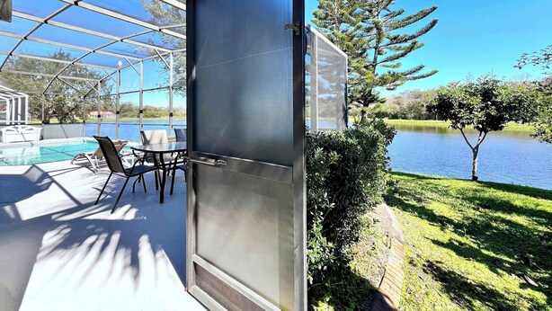 Un'area esterna coperta con piscina, sedie e vista su un lago.