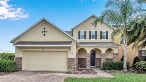 A two-story house with a garage, a cross on the roof, and a well-maintained lawn.
