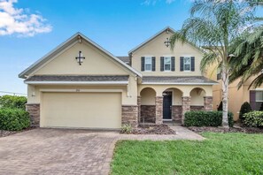 A two-story house with a garage, a cross on the roof, and a well-maintained lawn. - Pool Privacy! Value! Resort 8 mi 2 Disney! 1210 (Davenport)