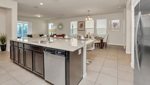 A modern kitchen with a central island, built-in dishwasher, and stainless steel appliances.