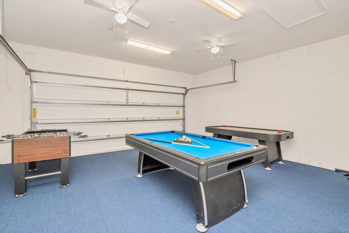 A room with a pool table, a foosball table, and a table tennis table.