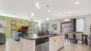 Una cocina moderna con lavavajillas, un comedor con sillas y vistas al exterior.