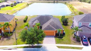 A residential area with houses, a large pond, and a paved driveway.