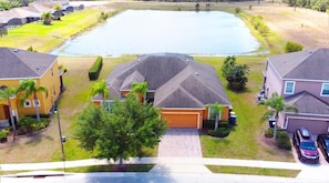 A residential area with houses, a large pond, and a paved driveway.