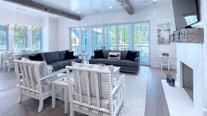 A spacious living room with a fireplace, large windows, and a modern TV.