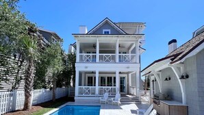 A two-story house with a swimming pool, a covered patio, and a barbecue area.