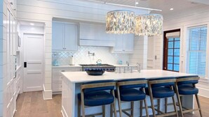 A modern kitchen with a large island, bar stools, and a unique chandelier.