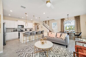 A modern kitchen with white cabinets, a central island, and bar stools. - Private Pool | Lazy River | Resort Pool | Disney 108 (Davenport)