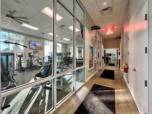 A fitness center with exercise equipment, a ceiling fan, and a sign for the fitness center.