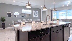 A modern kitchen with a granite countertop, dark cabinetry, and pendant lighting. - Star Wars | Themed Rooms | Resort Near Disney 2061 (Davenport)