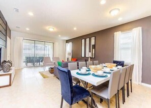 Un comedor moderno con una mesa blanca dispuesta para seis personas, rodeada de sillas.