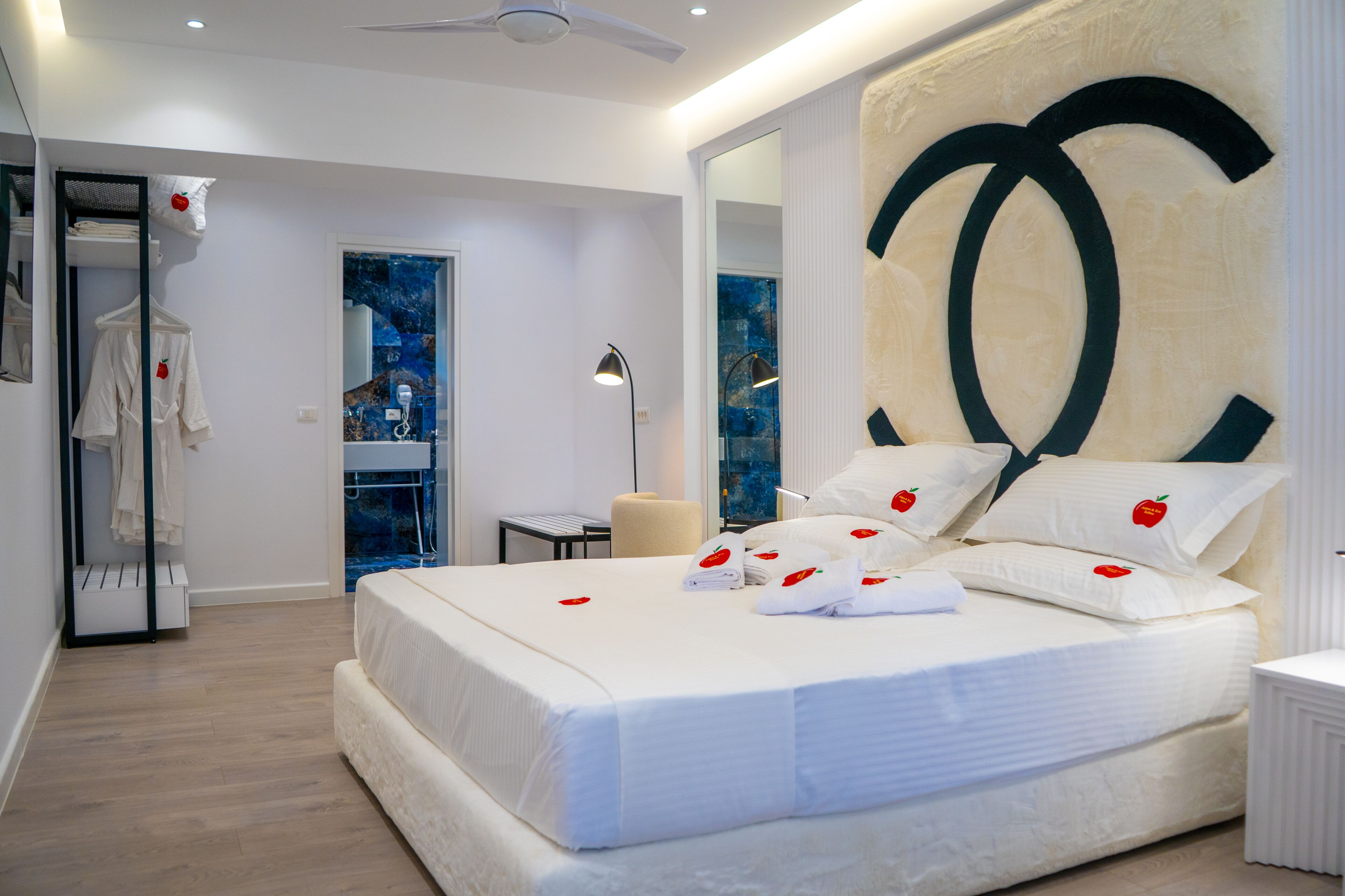 A modern hotel room with a large bed, a mirror, and a view of the city.