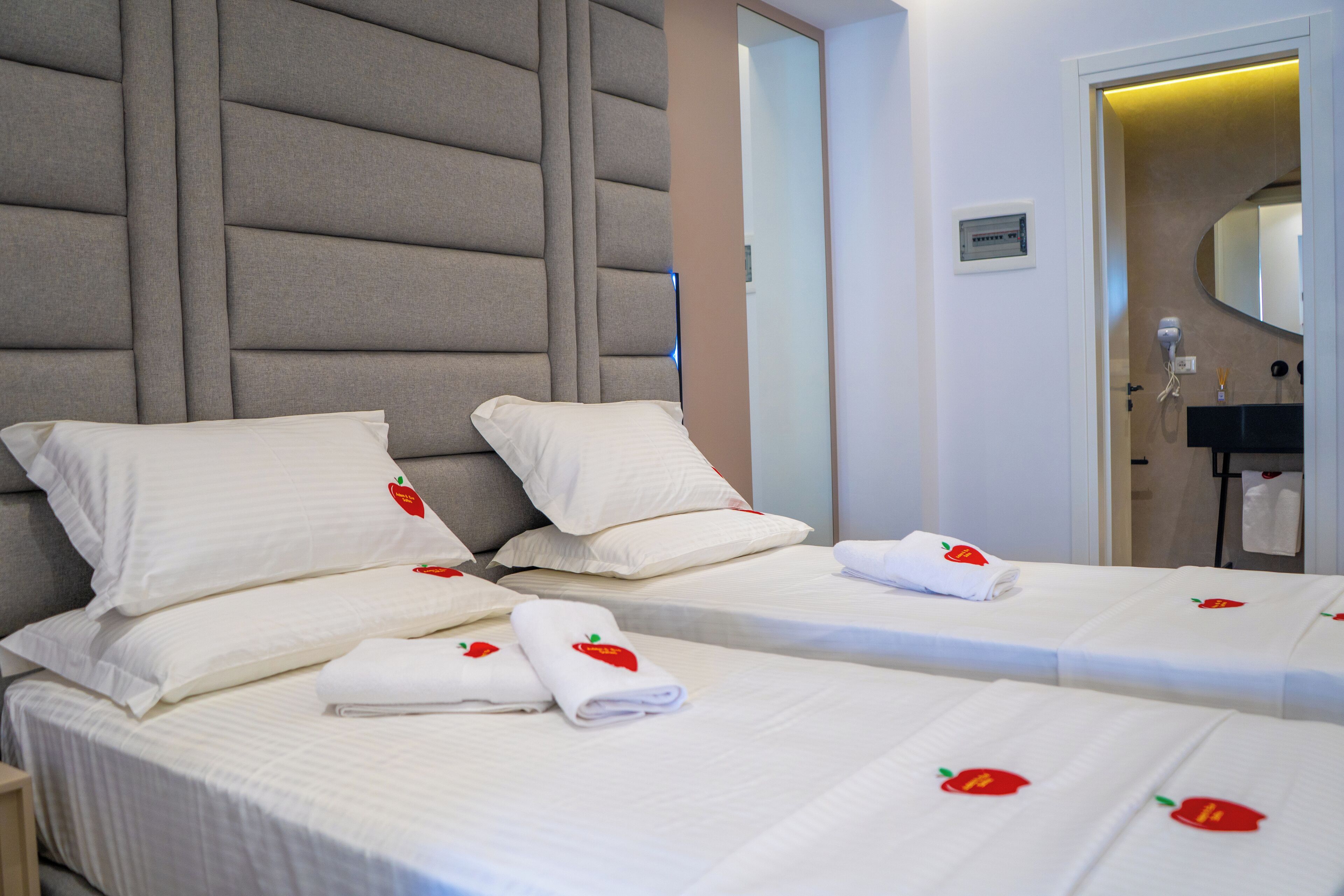 Een hotelkamer met twee bedden, elk voorzien van witte beddengoed en kussens, en een hoofdbord met een gestructureerd ontwerp.
