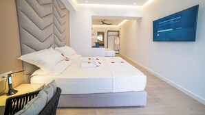 Una habitación de hotel moderna con una cama grande, un escritorio y un televisor de pantalla plana montado en la pared.