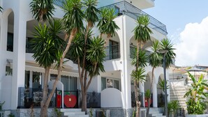 Un edificio de varios pisos con balcones, palmeras y cielo despejado.