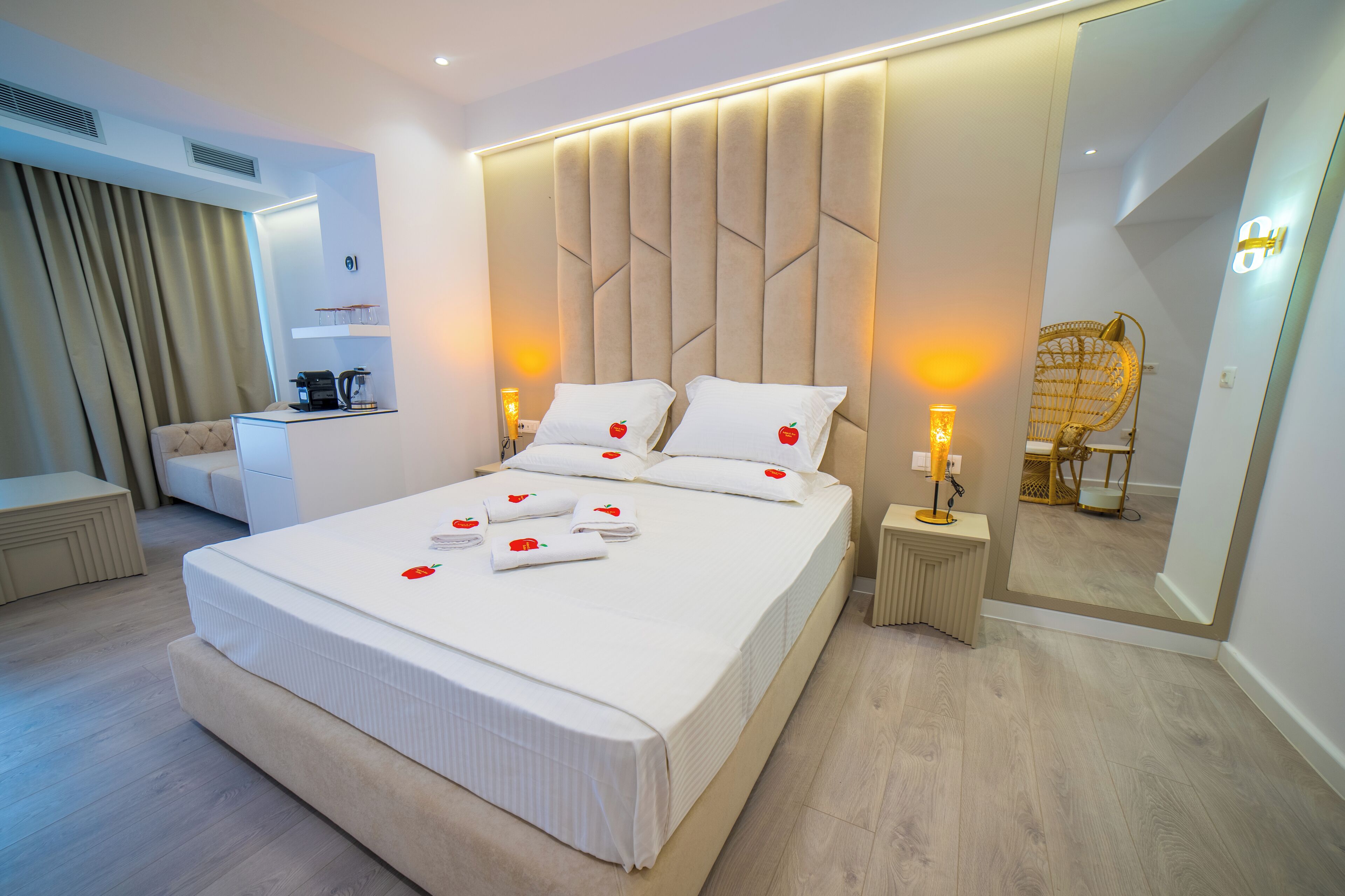 Een moderne hotelkamer met een groot bed, nachtkastjes, een bureau en een spiegel.