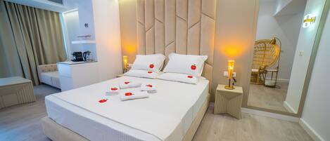 Een moderne hotelkamer met een groot bed, nachtkastjes, een bureau en een spiegel.