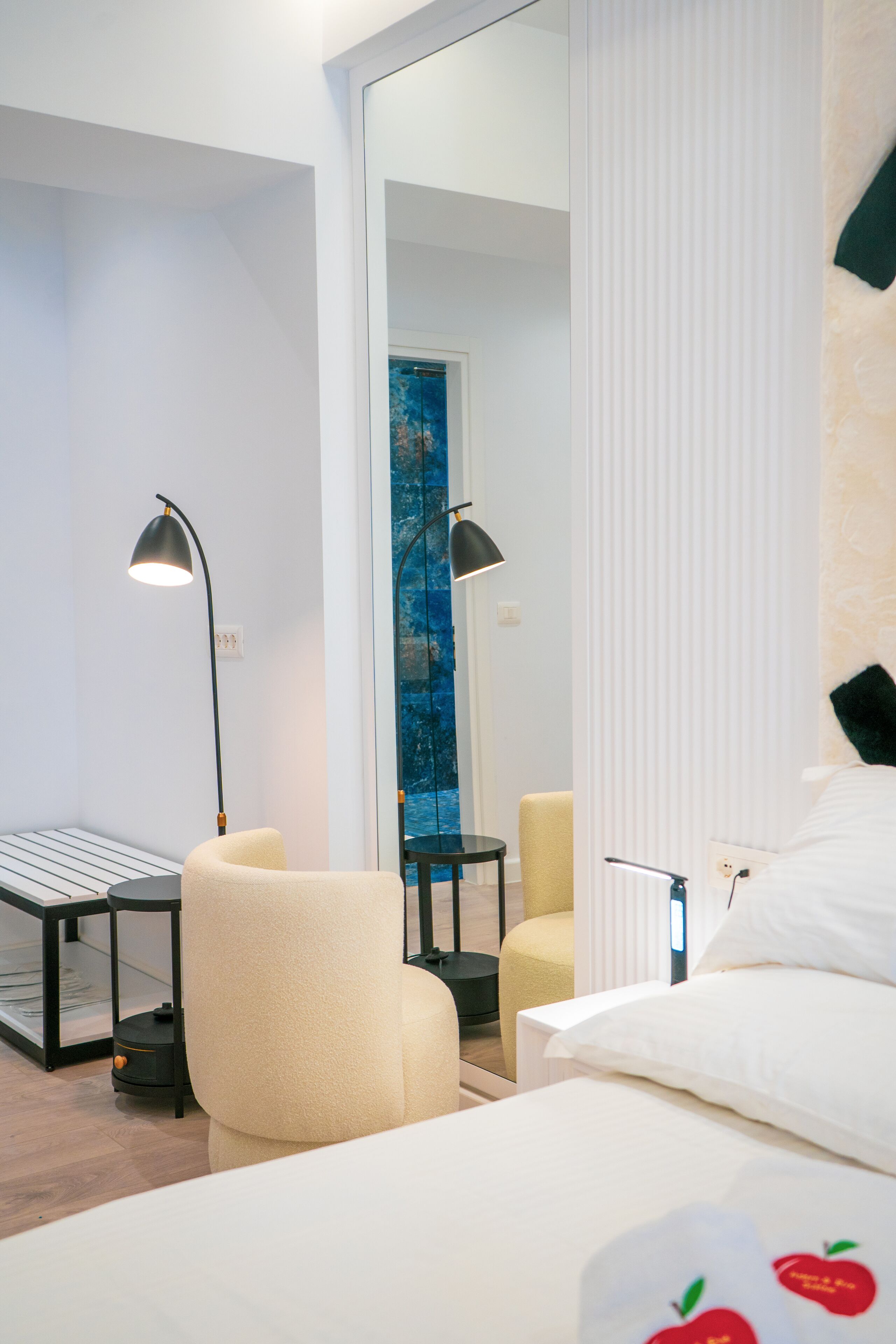 A modern hotel room with a bed, a desk, a chair, and a large mirror.