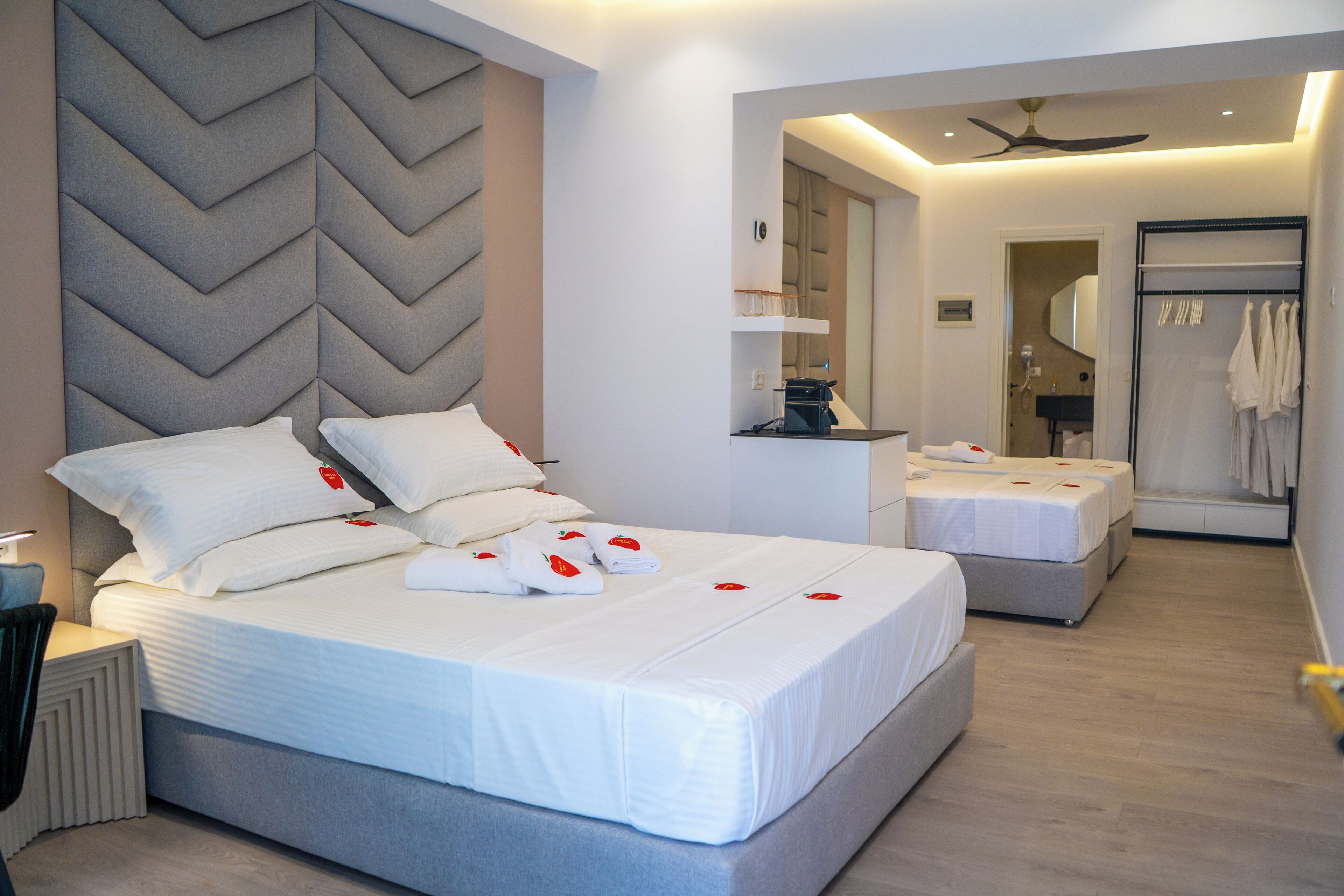 Une chambre d’hôtel moderne dotée d’un grand lit, d’un coin salon séparé, d’une coiffeuse et d’un dressing.