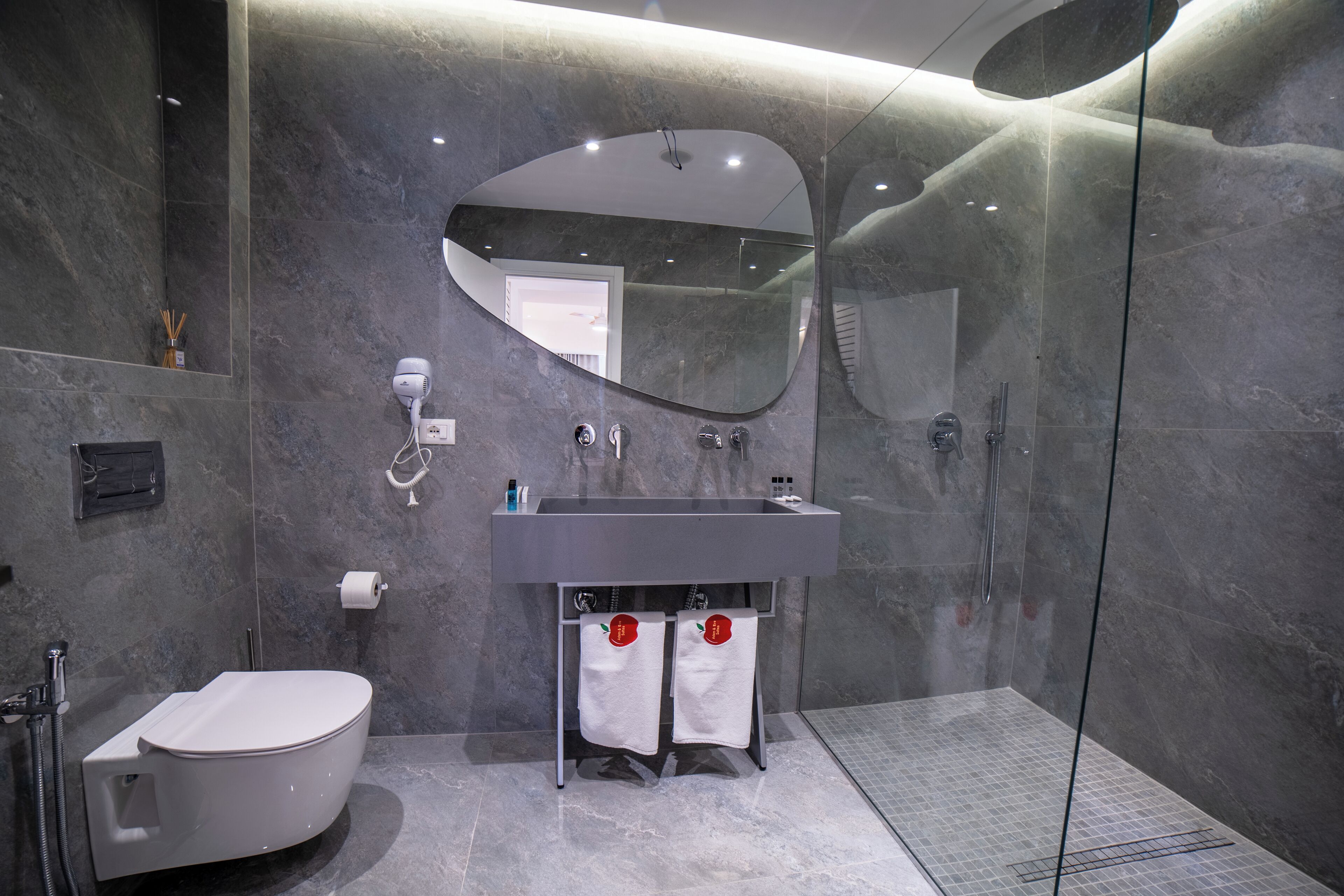 A modern bathroom with a freestanding bathtub, a large mirror, and a glass-enclosed shower area.