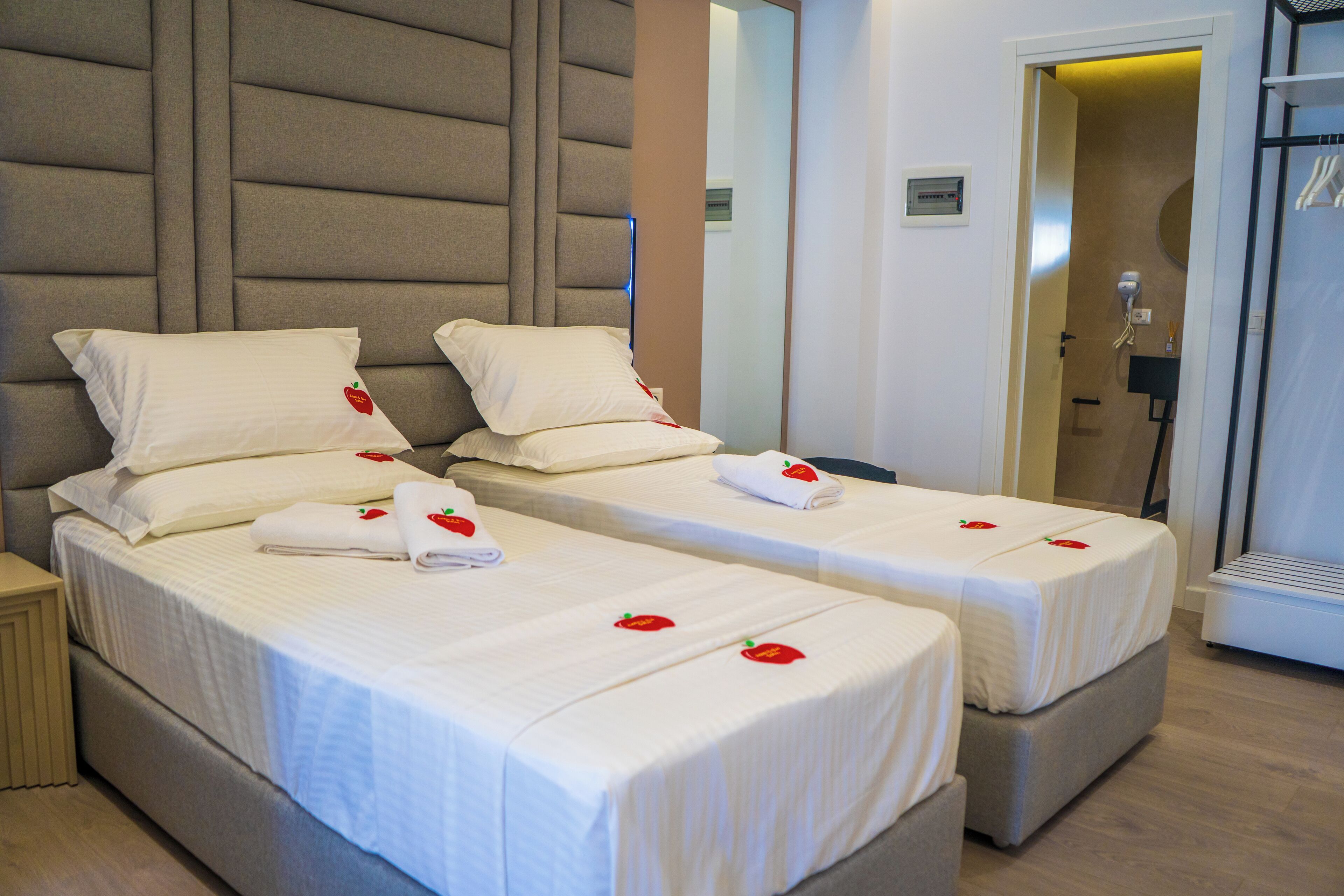 Two single beds with white linens and rose petals, a headboard, and a mirror.